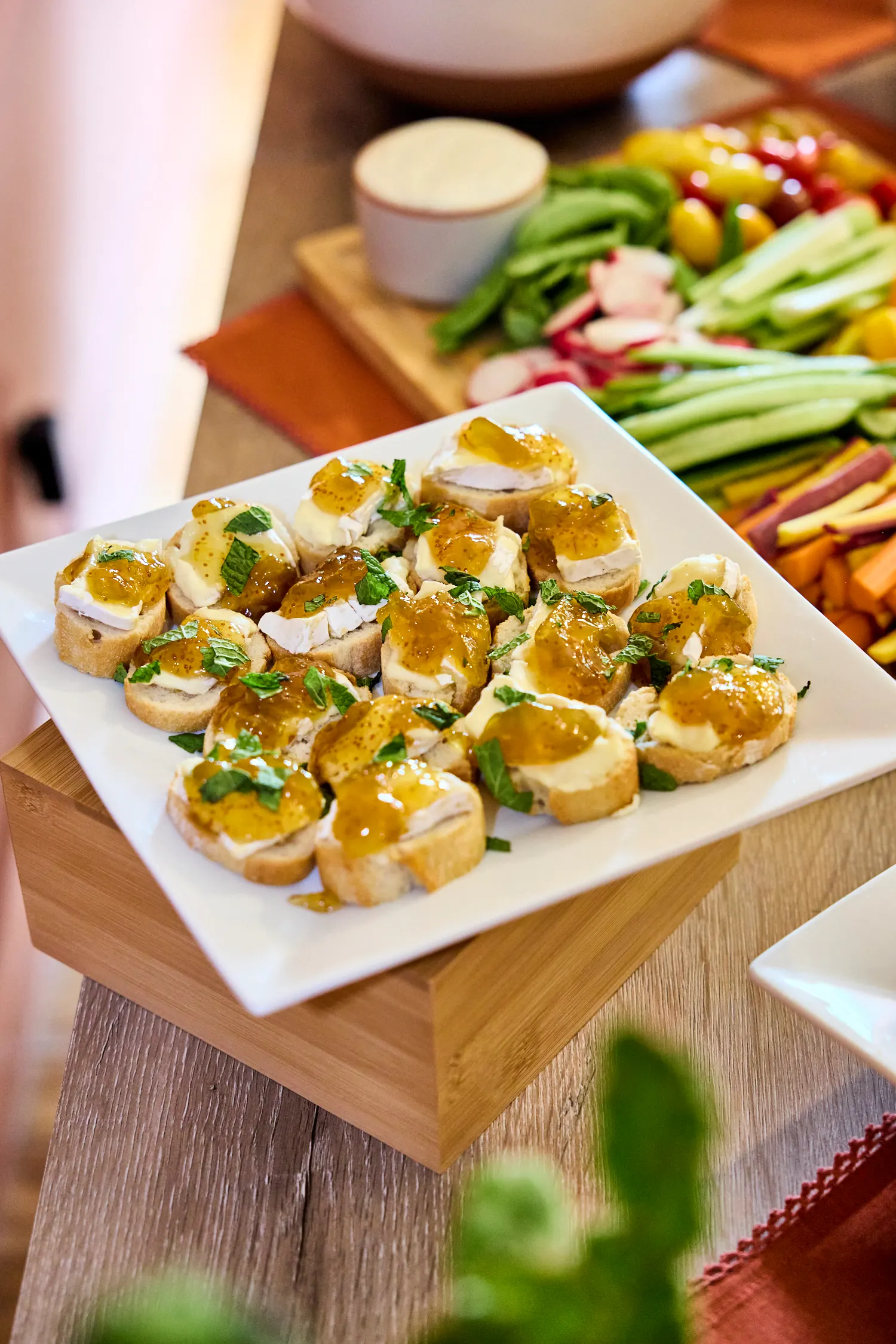 Brie and fig jam crostini with mint on a white platter, Del Sol