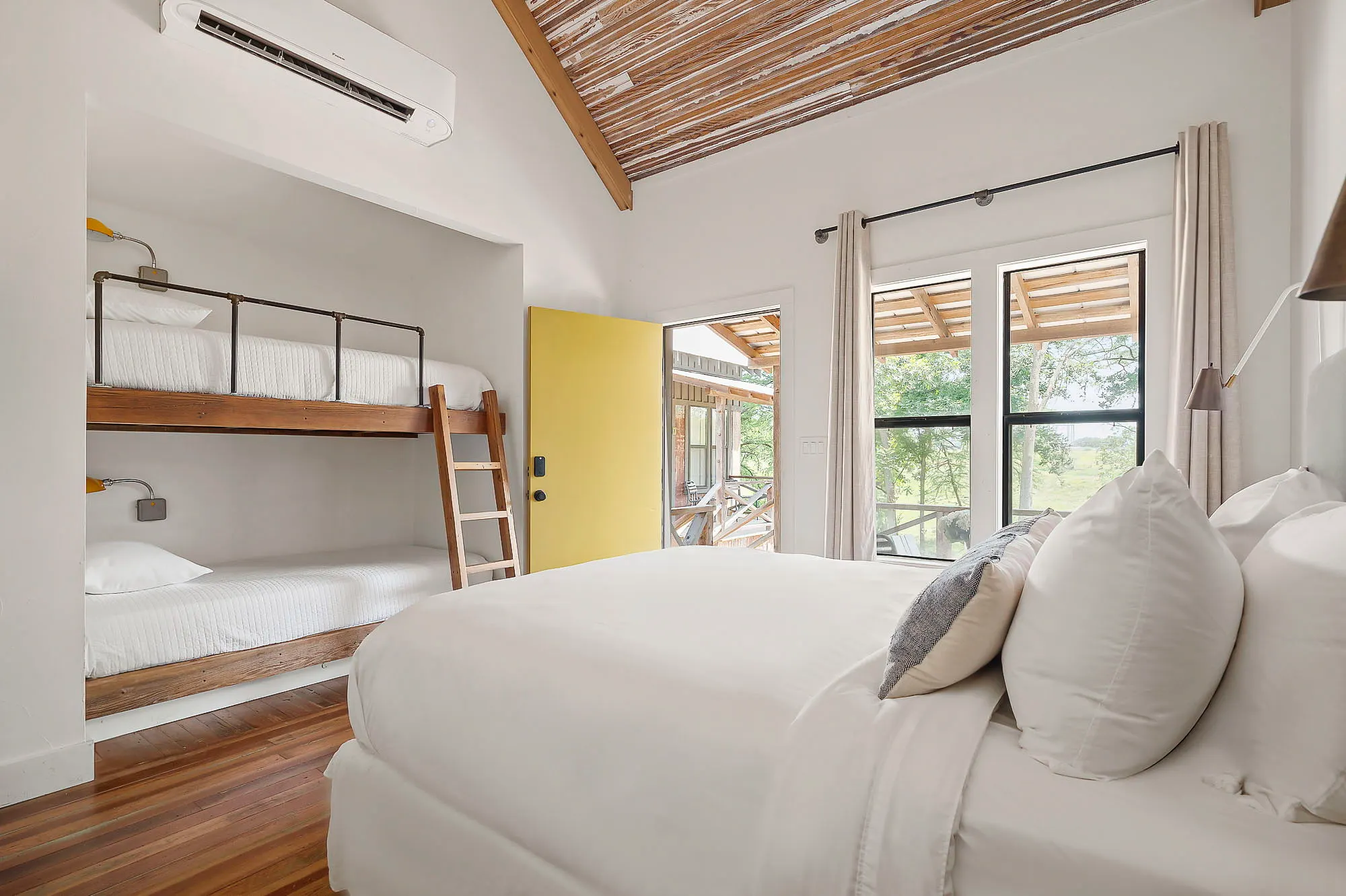 Bunk room with a king bed, built-in bunks and a yellow door onto the porch, Camp Comfort