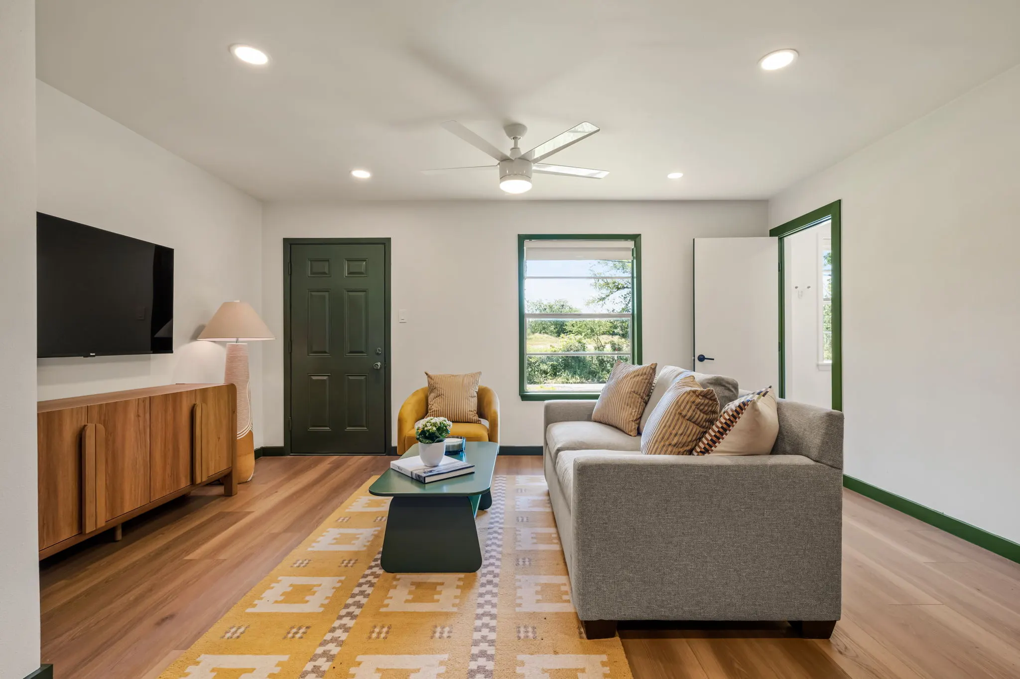 Living room with a yellow rug, green door and gold accent chair, Petit Cowboy