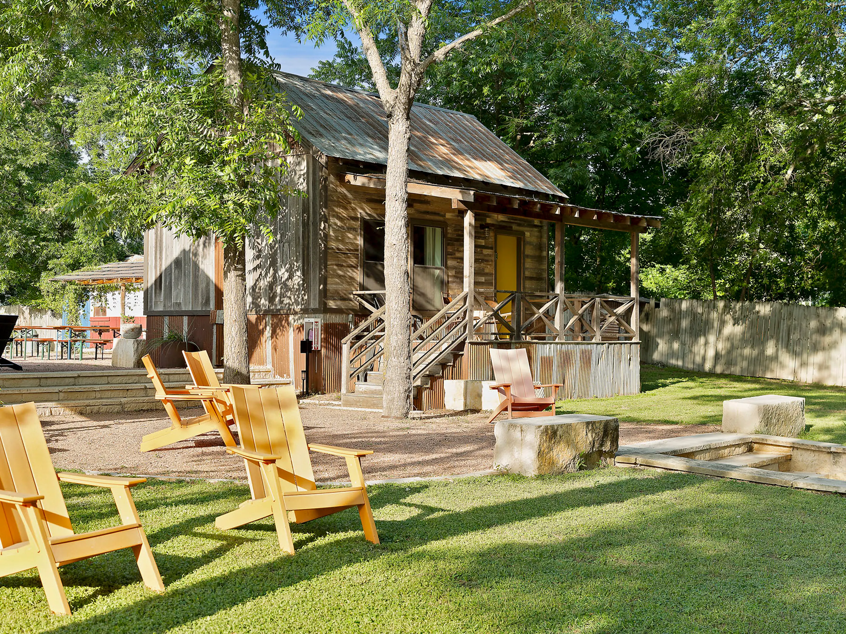 Weathered cabin with a yellow door and Adirondack chairs on the lawn, Camp Comfort