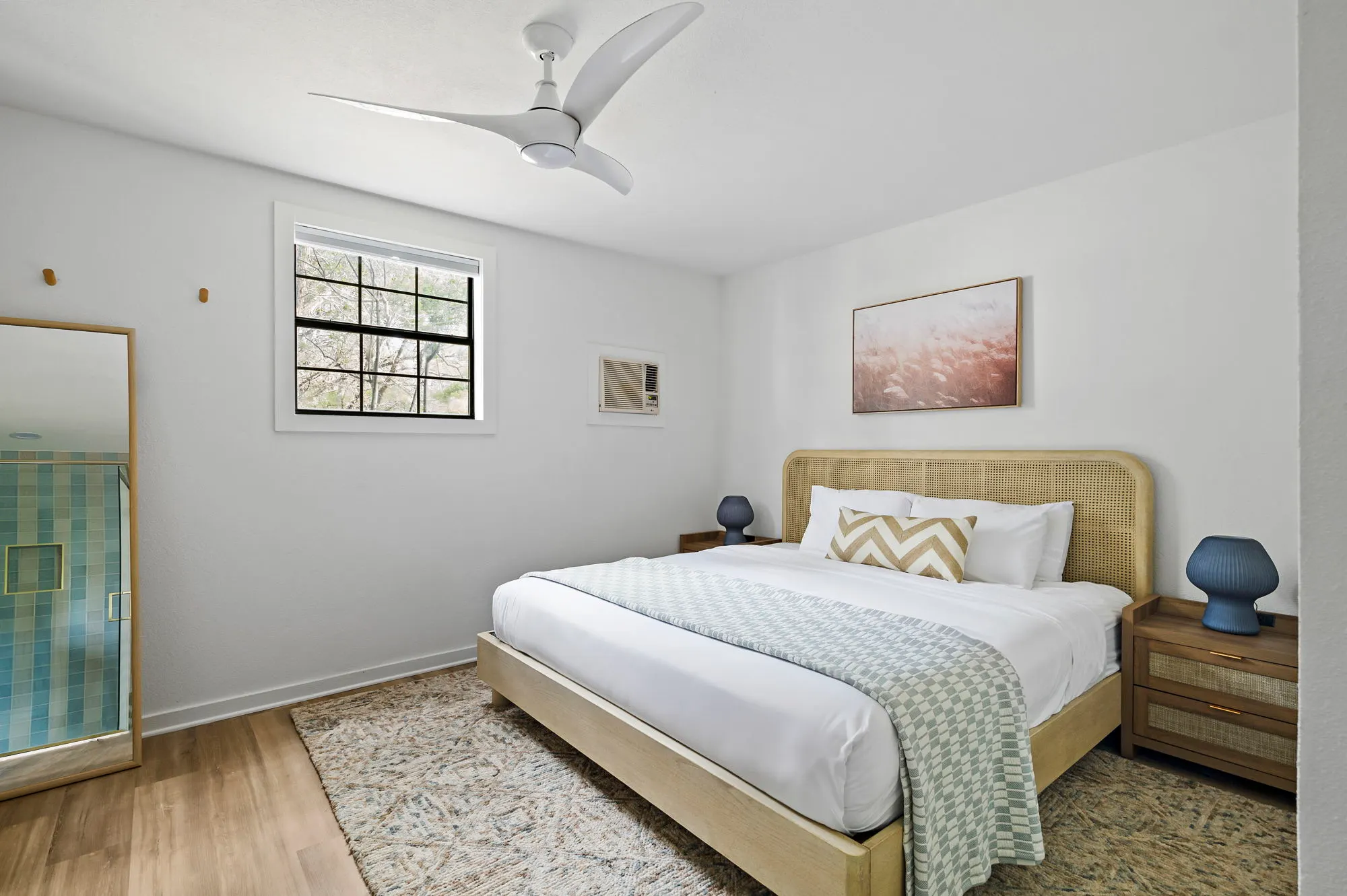 Guest room with a cane bed, blue lamps and a woven rug, The Claire Hotel