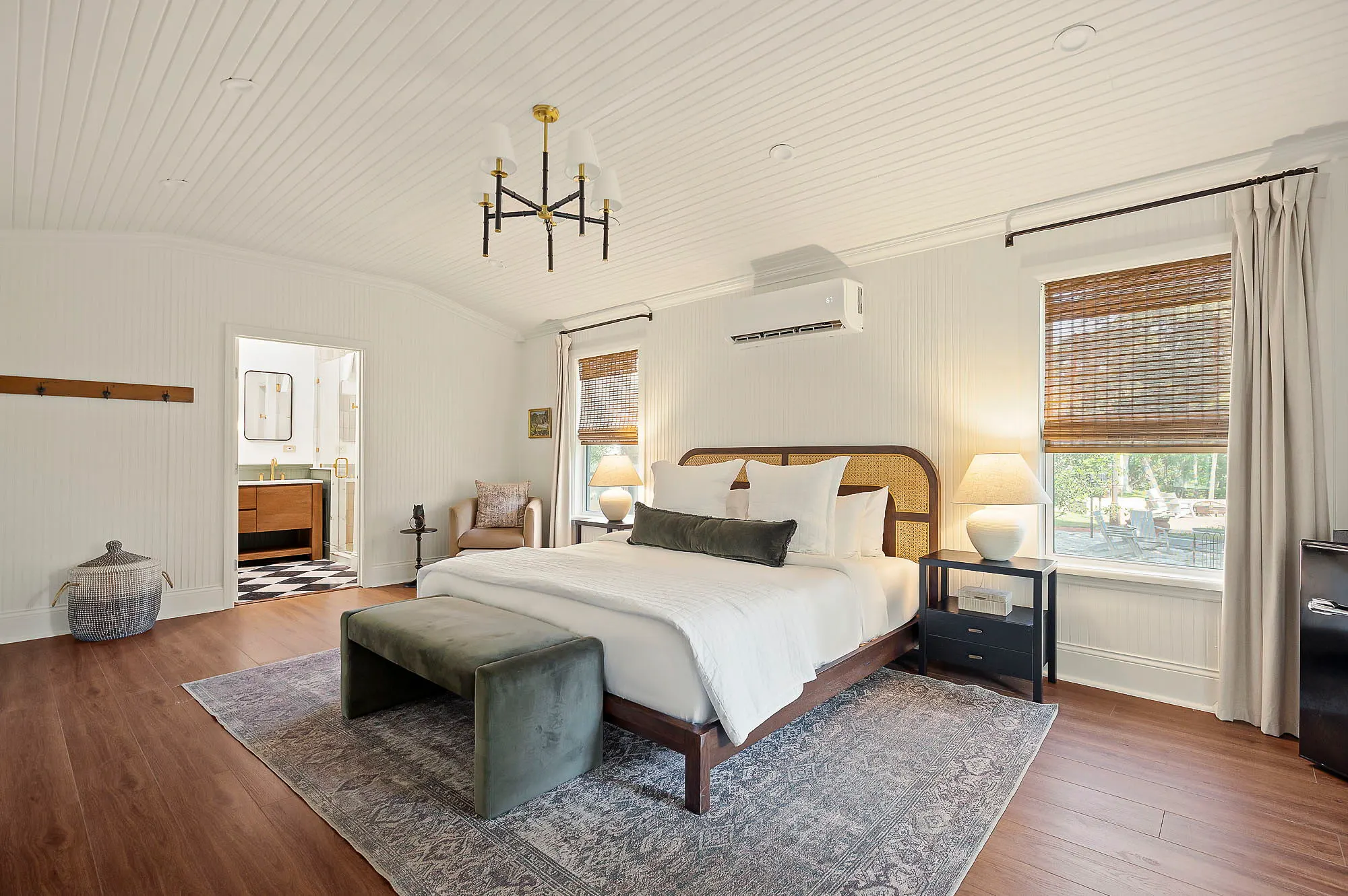 Beadboard king room with a cane headboard, velvet bench and bamboo shades, The Meyer Hotel