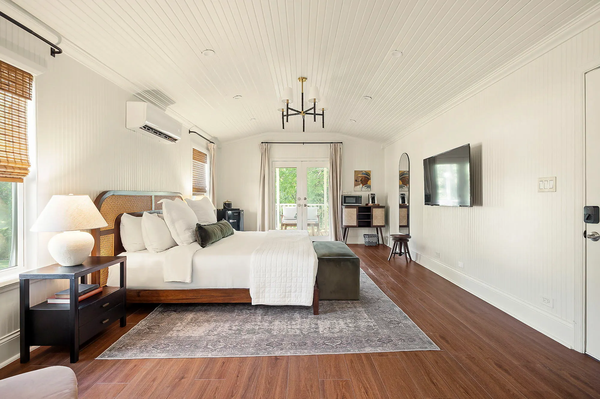 Long suite with a cane king bed, chandelier and doors onto the porch, The Meyer Hotel