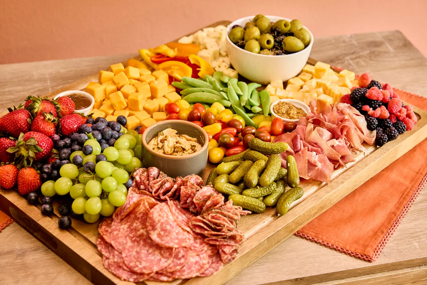 A loaded charcuterie board: salami, prosciutto, cheddar, cornichons, olives and fruit, Del Sol