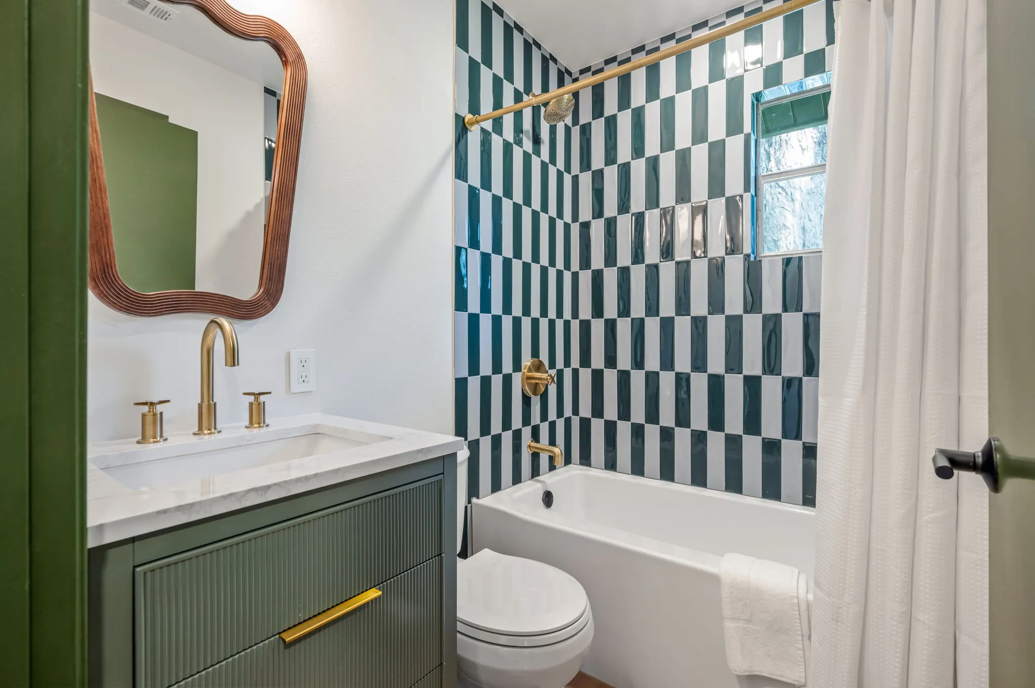 Bath with green checkerboard tile and a wavy mirror, Petit Cowboy