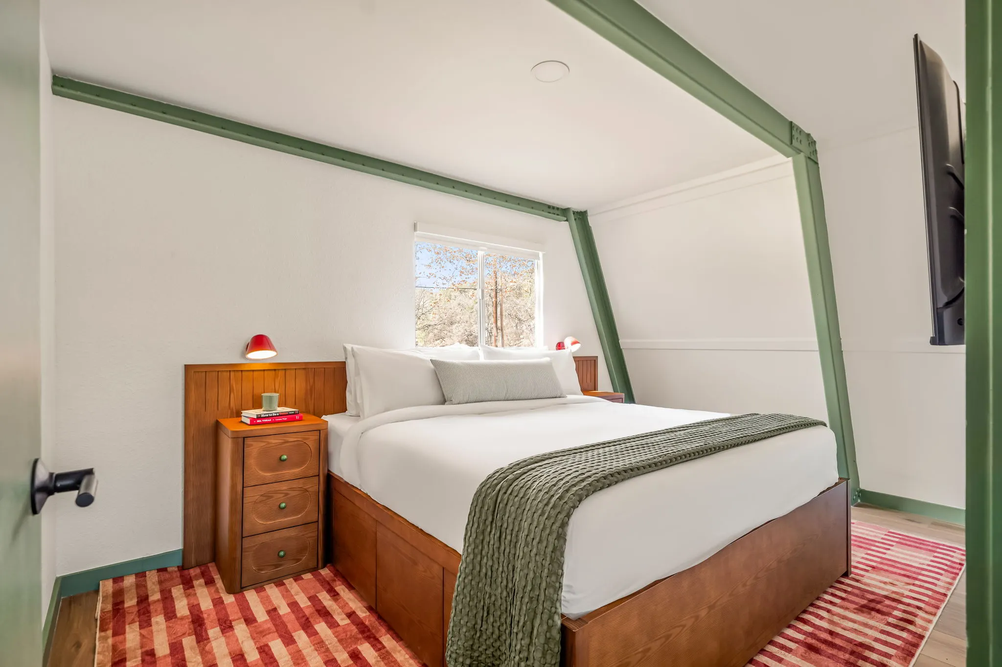 King bedroom under a green gambrel beam with a red striped rug, Petit Cowboy