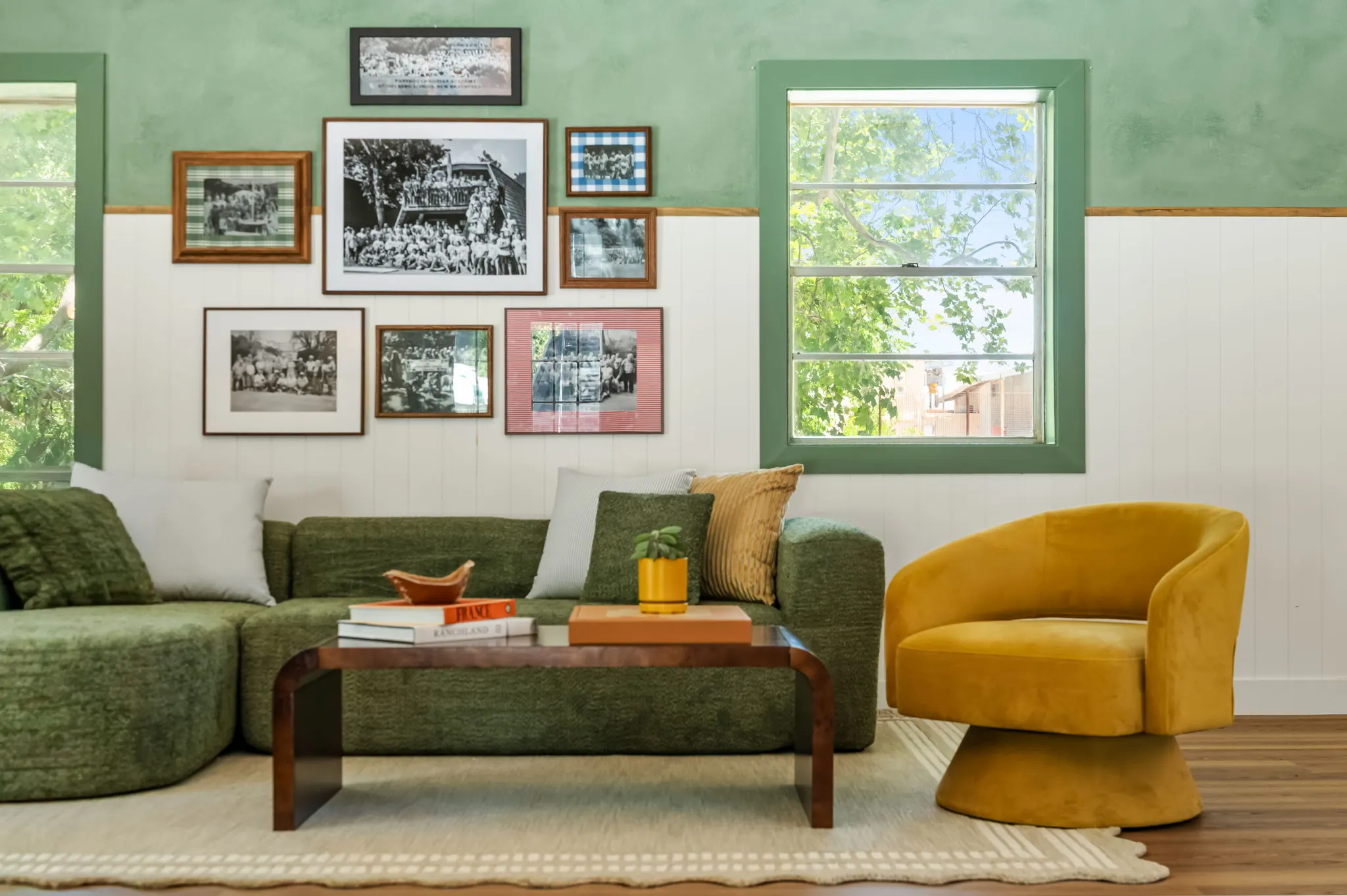 Green lounge with a mossy sectional, a mustard swivel chair and a wall of framed camp photographs, Petit Cowboy