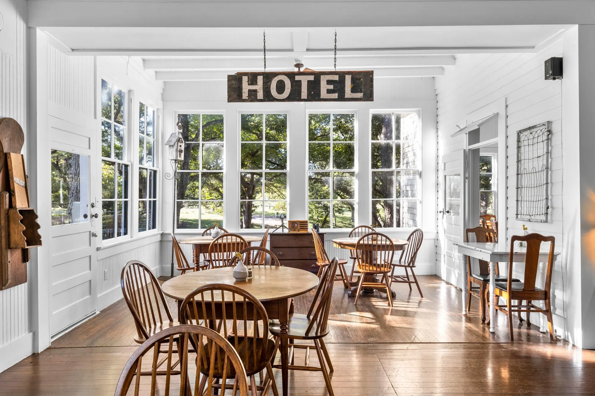 Sunlit dining porch with Windsor chairs under the original HOTEL sign, The Meyer Hotel