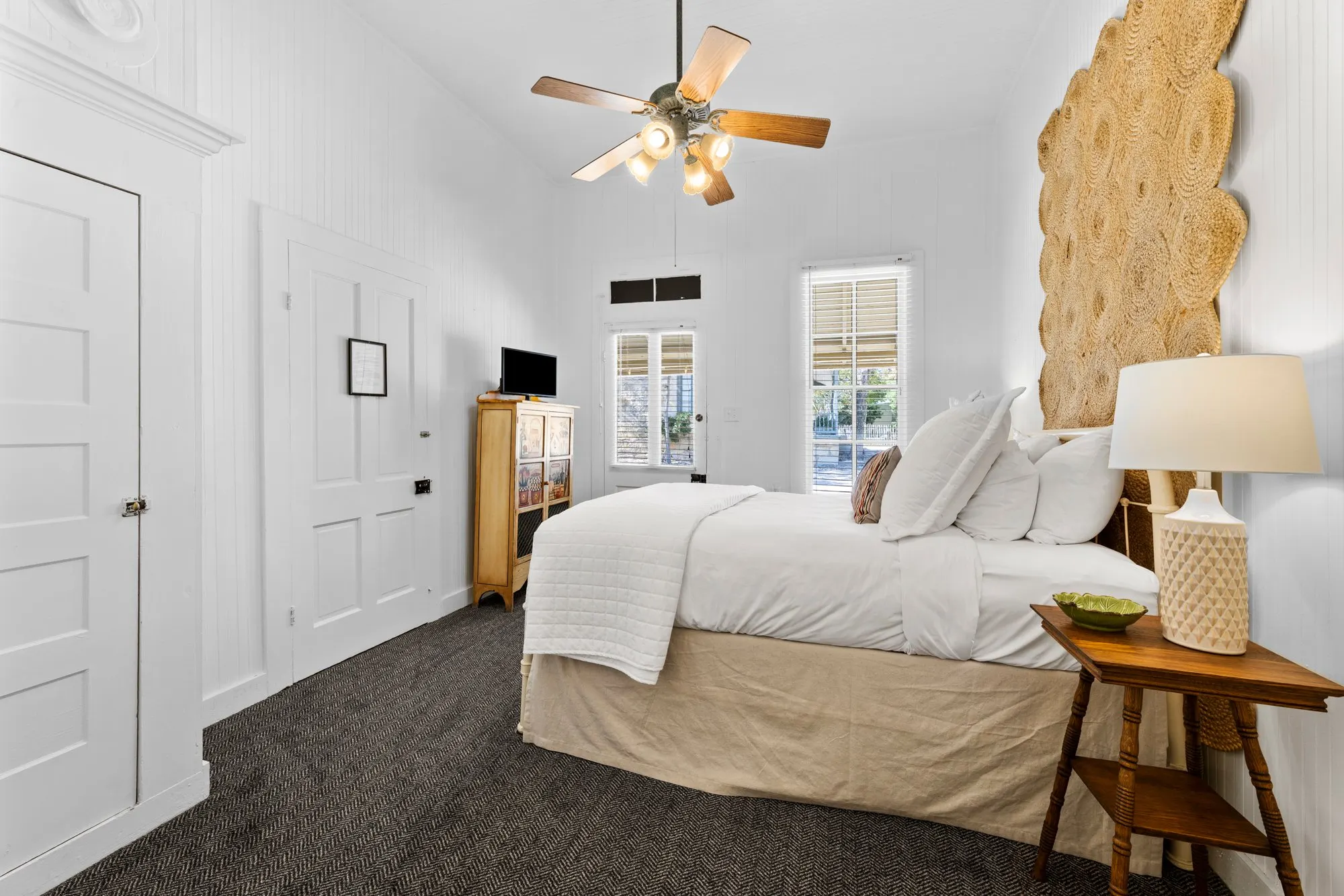 Beadboard room with a tall woven jute headboard and a window onto the porch, The Meyer Hotel