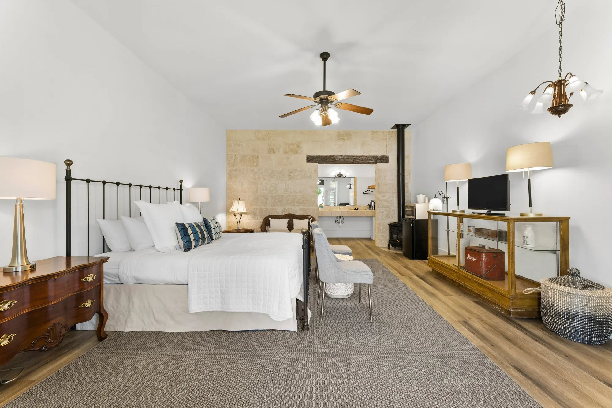King room with an iron bed, a limestone vanity wall and an antique glass display case, The Meyer Hotel