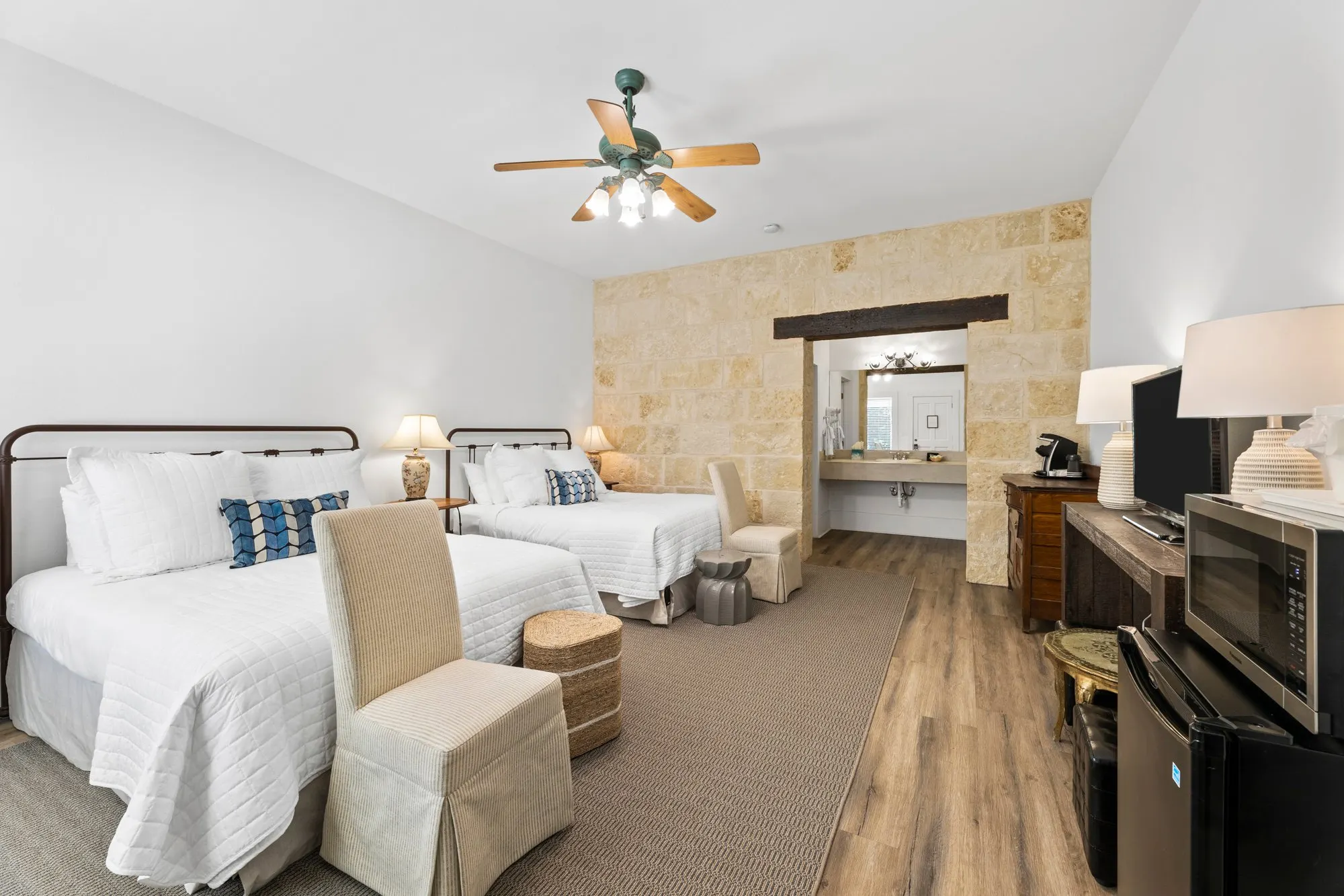 Two-queen room with iron beds and a limestone wall around the vanity, The Meyer Hotel