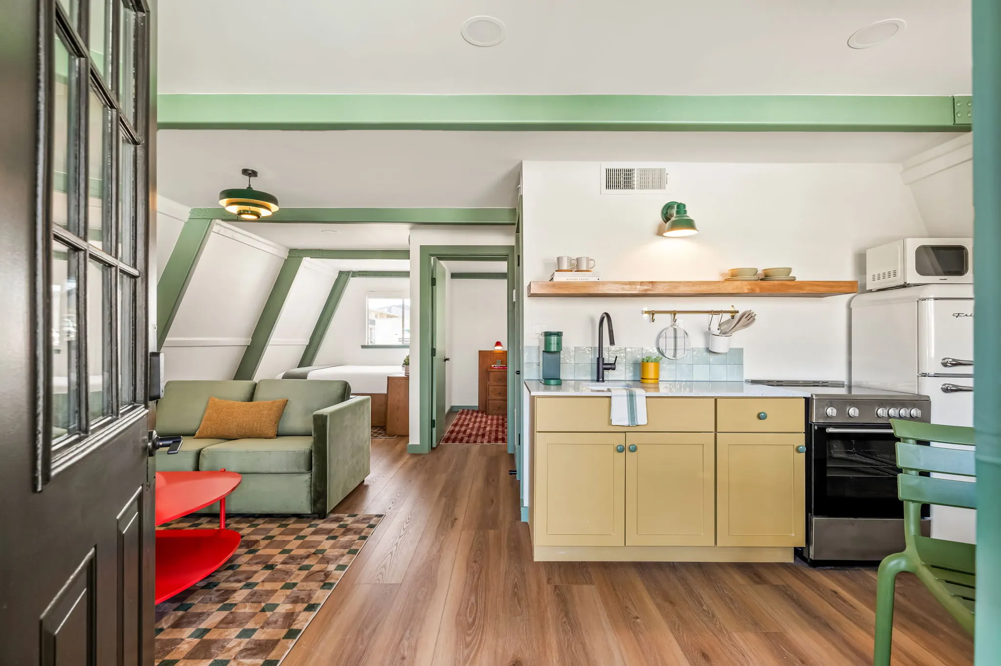 Loft suite from the door: green beams, sofa and yellow kitchen, Petit Cowboy