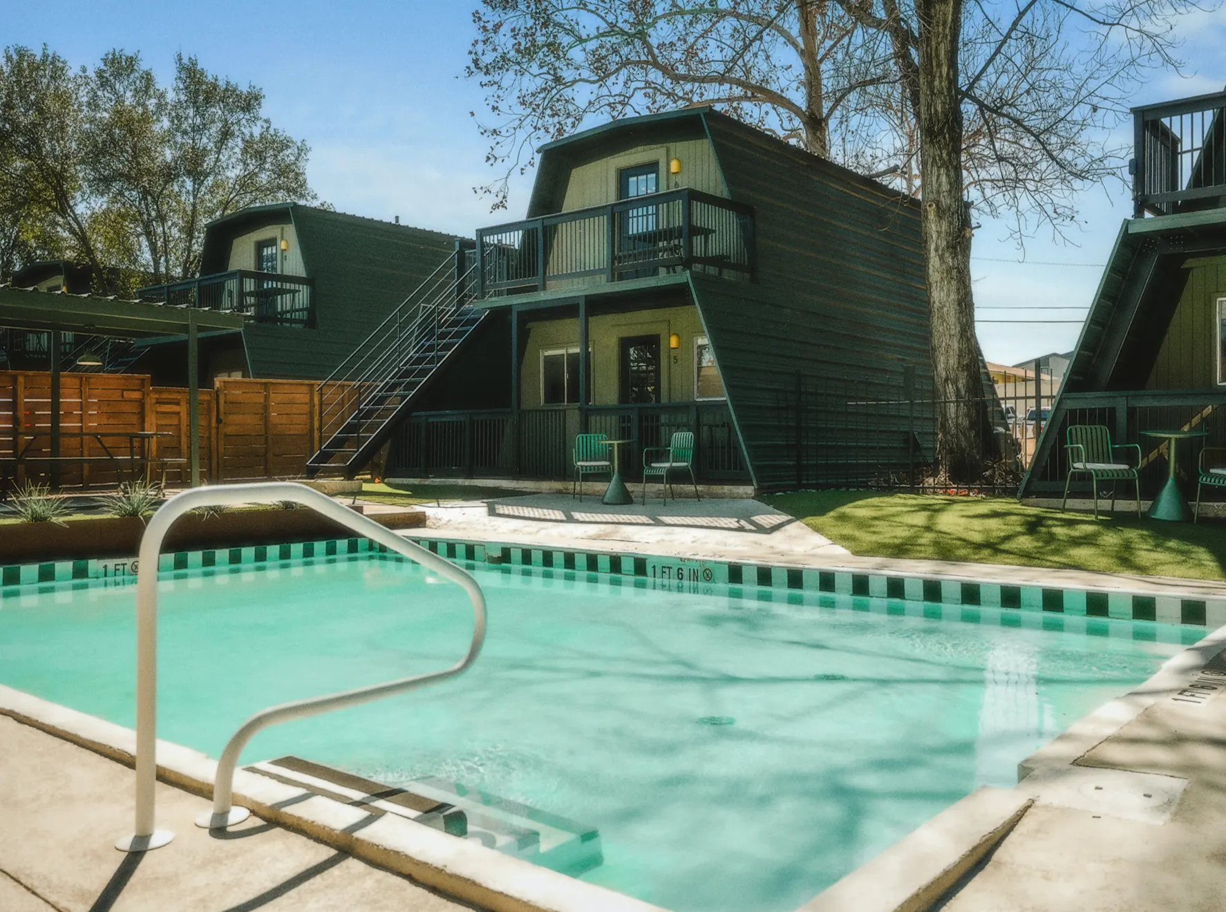 Pool with green tile stripe, the A-frame cabins and balconies behind it, Petit Cowboy