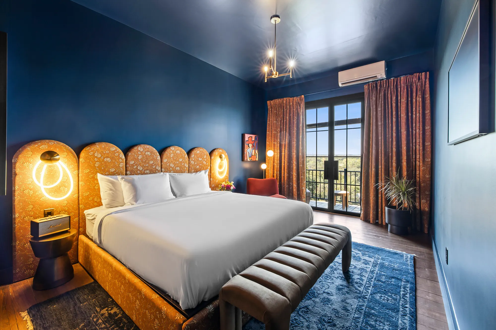 Blue guest room with a floral arched headboard and river view, Gruene River Inn