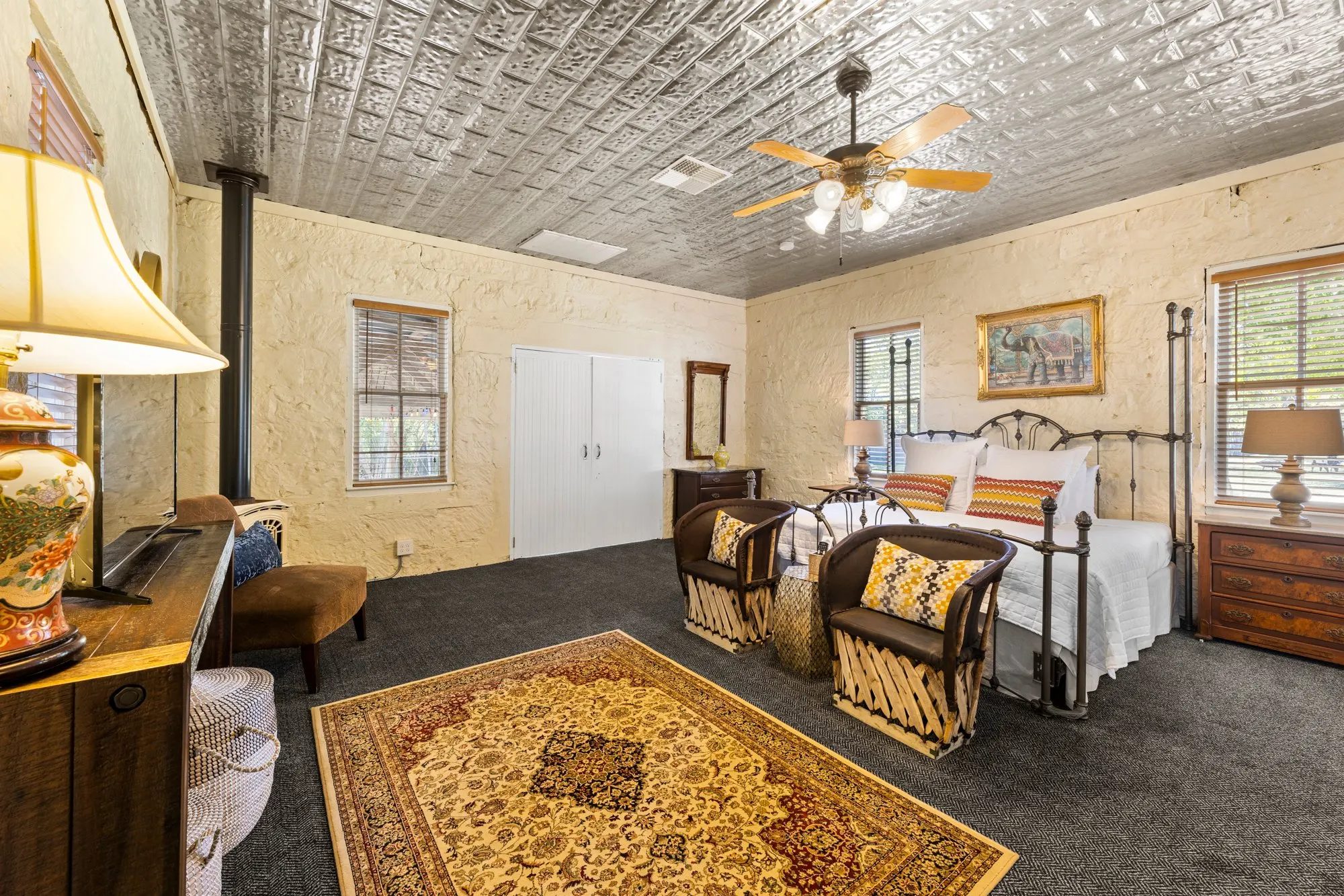 Stone guest room with an iron bed and pressed-tin ceiling, The Meyer Hotel
