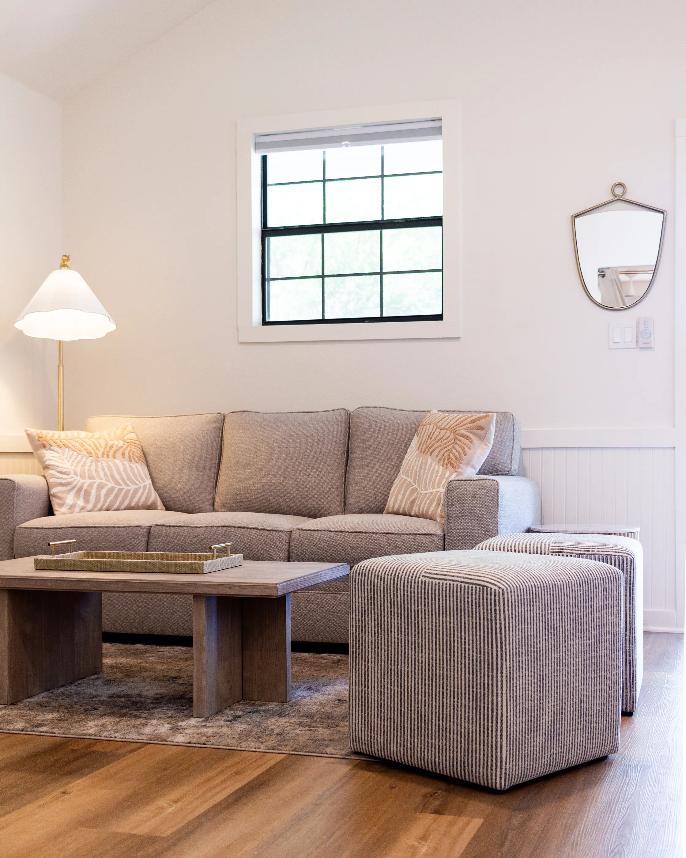 Suite sitting room with a linen sofa, striped ottomans and a black-sash window, The Claire Hotel
