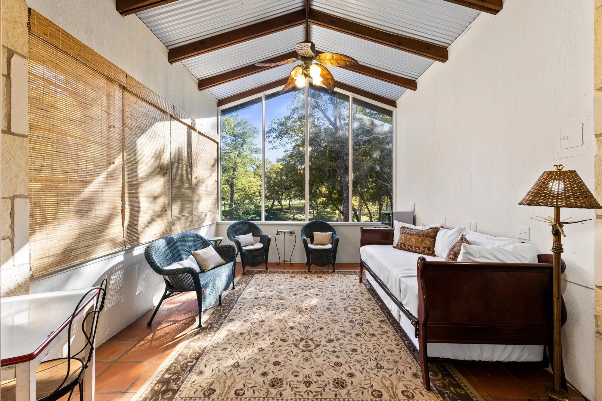 Sunporch with wicker chairs, tile floor and a view of the creek lawn, The Meyer Hotel