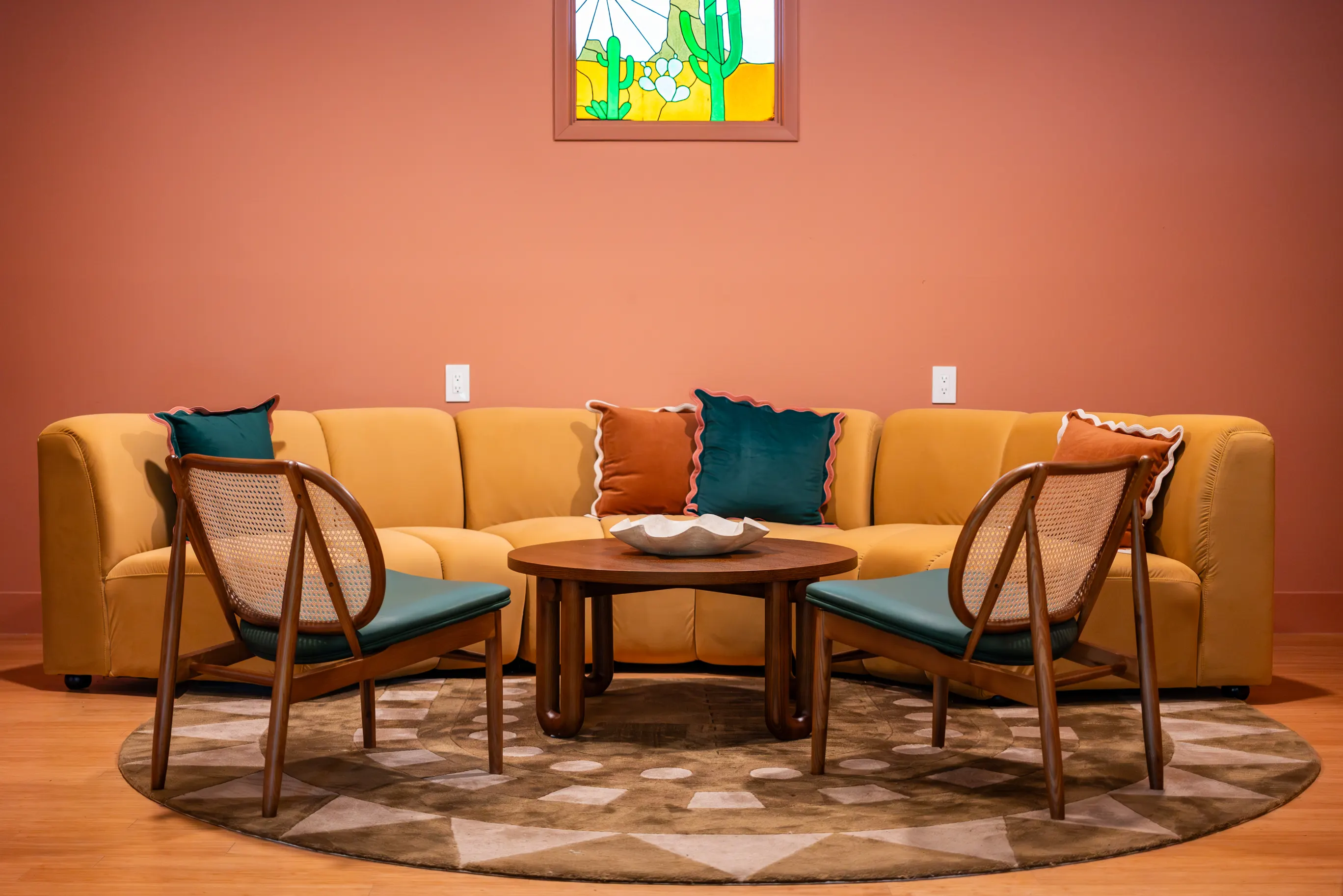 Terracotta sitting room with a yellow sectional, cane chairs and a stained-glass cactus window, Hacienda del Rio