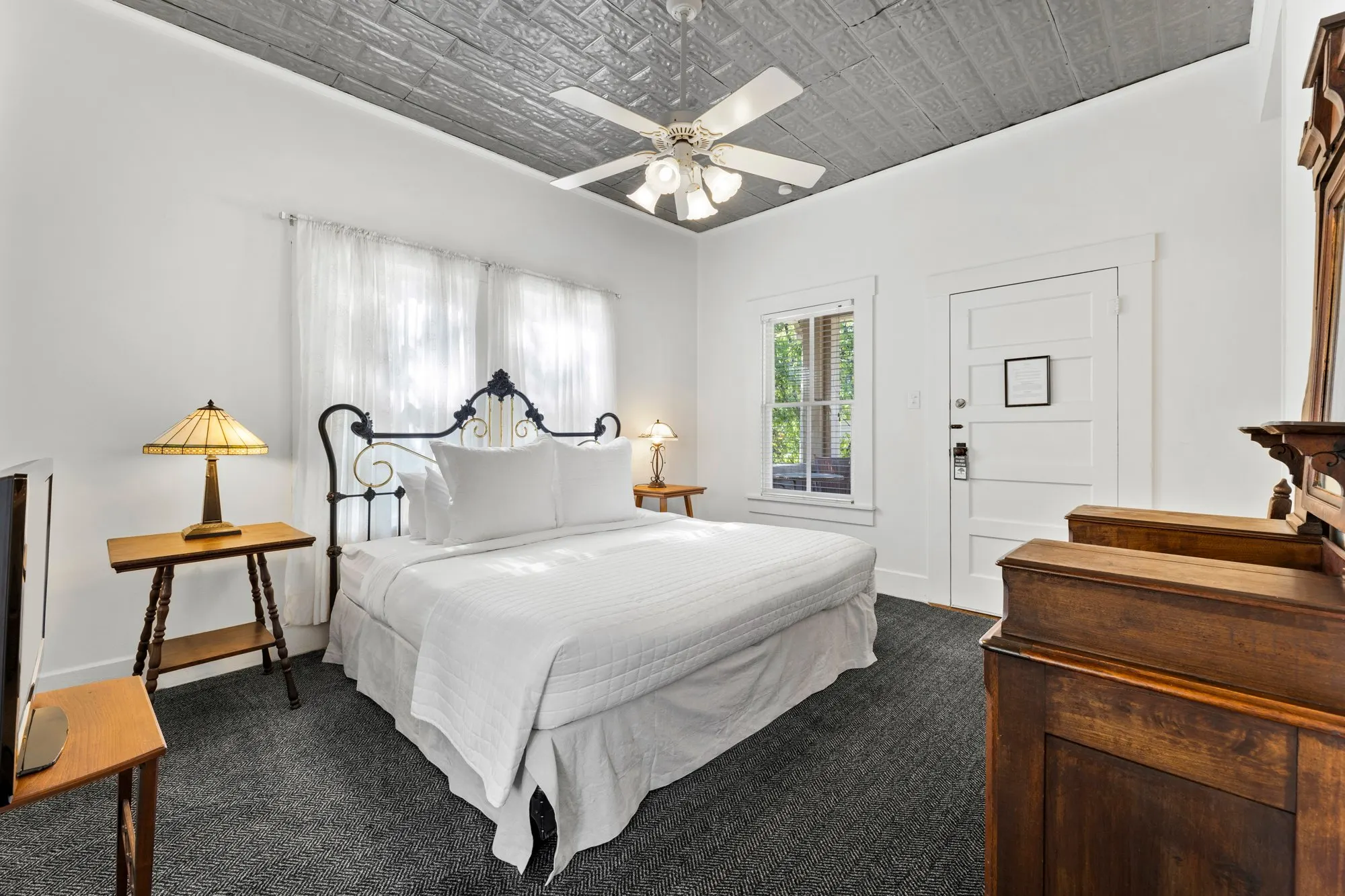 White guest room with an antique iron bed under pressed tin, The Meyer Hotel