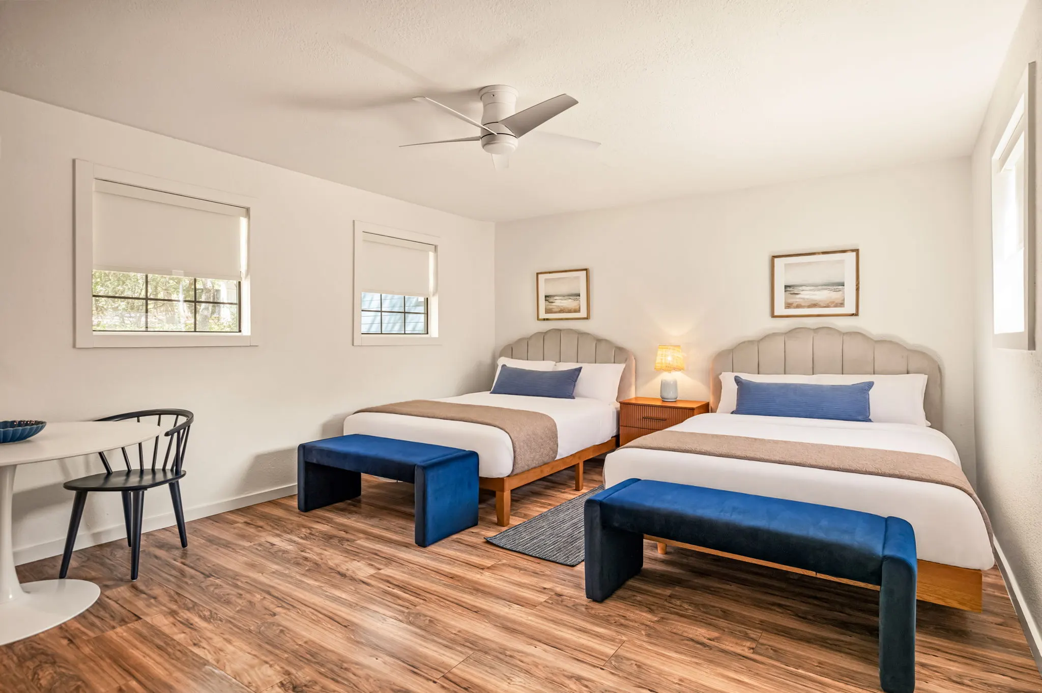 Two-queen room with scalloped headboards and navy velvet benches, The Claire Hotel