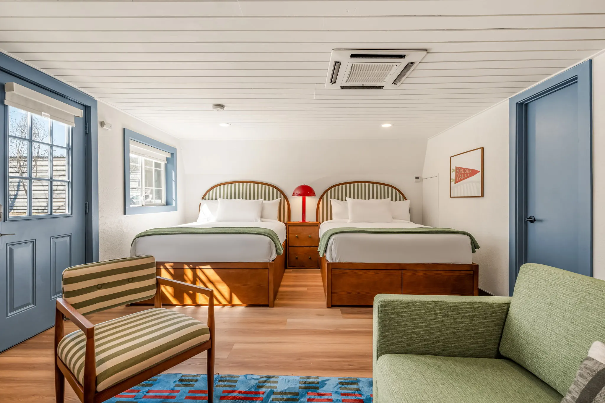 Two-queen suite with arched striped headboards and a red lamp, Petit Cowboy