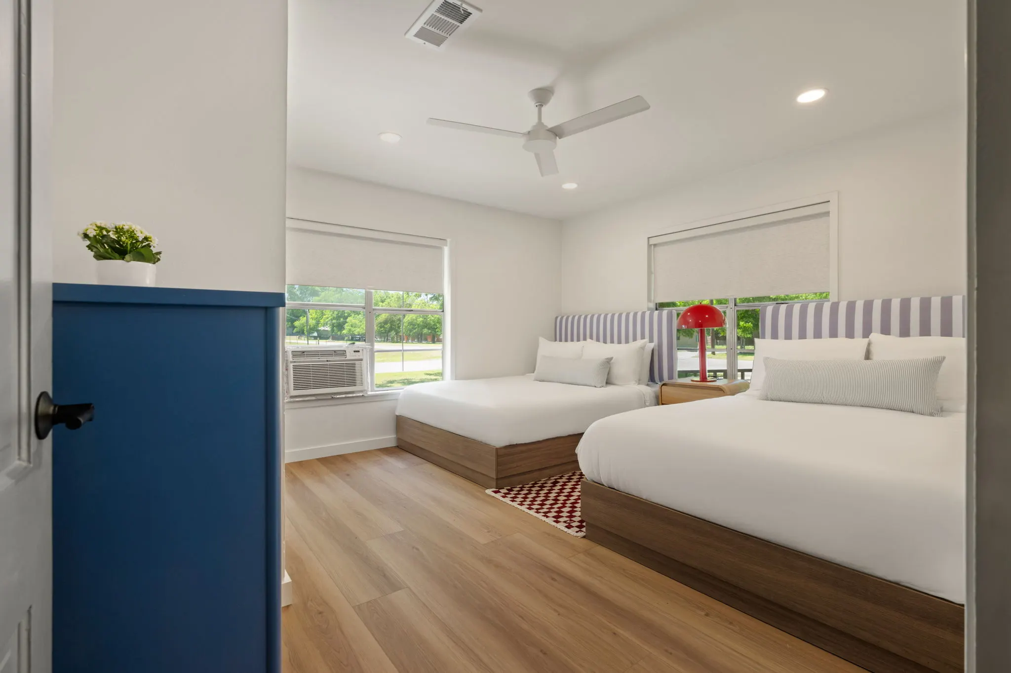 Two-queen room with striped headboards and a red lamp, Petit Cowboy